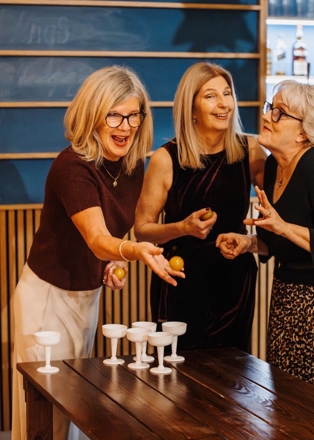 Two women play beer pong at engagement party.