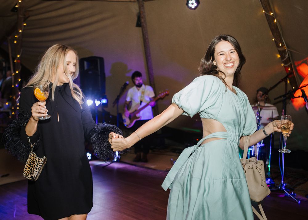 Party guests dancing and celebrating at an evening reception with ambient lighting.