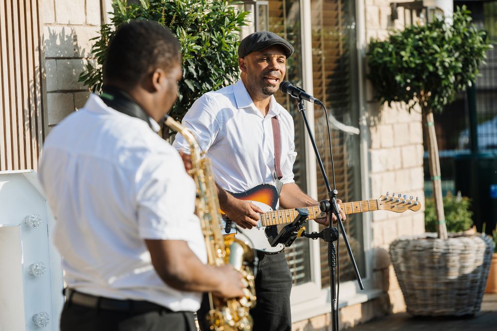 Musicians performing outdoors with saxophones and instruments in white attire.