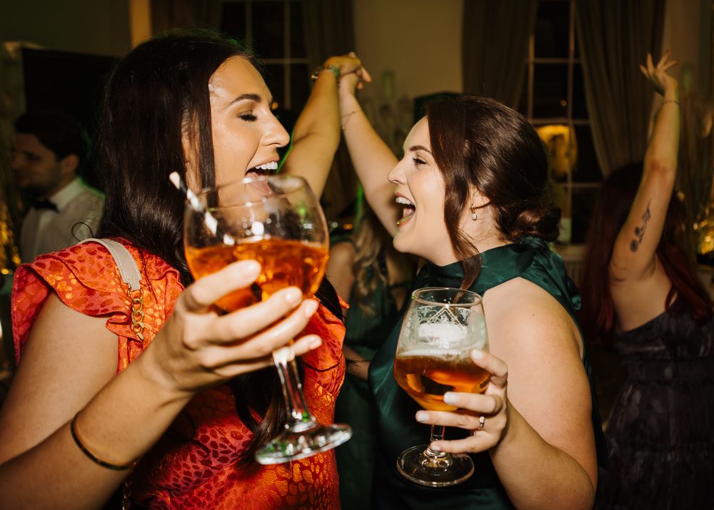 Two friends enjoying dancing with drinks.