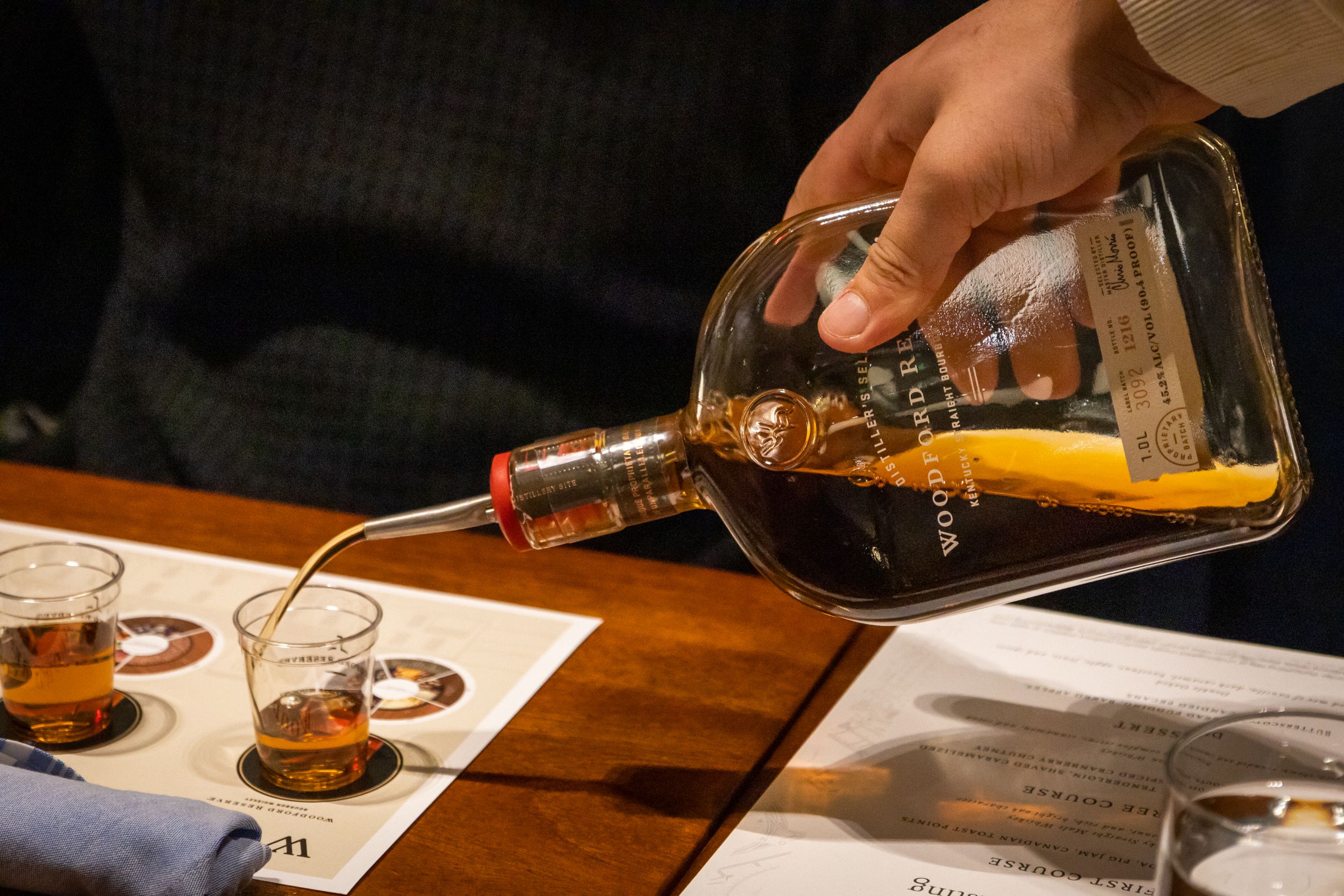 Amber liquid being carefully poured from a glass decanter during a tasting session.