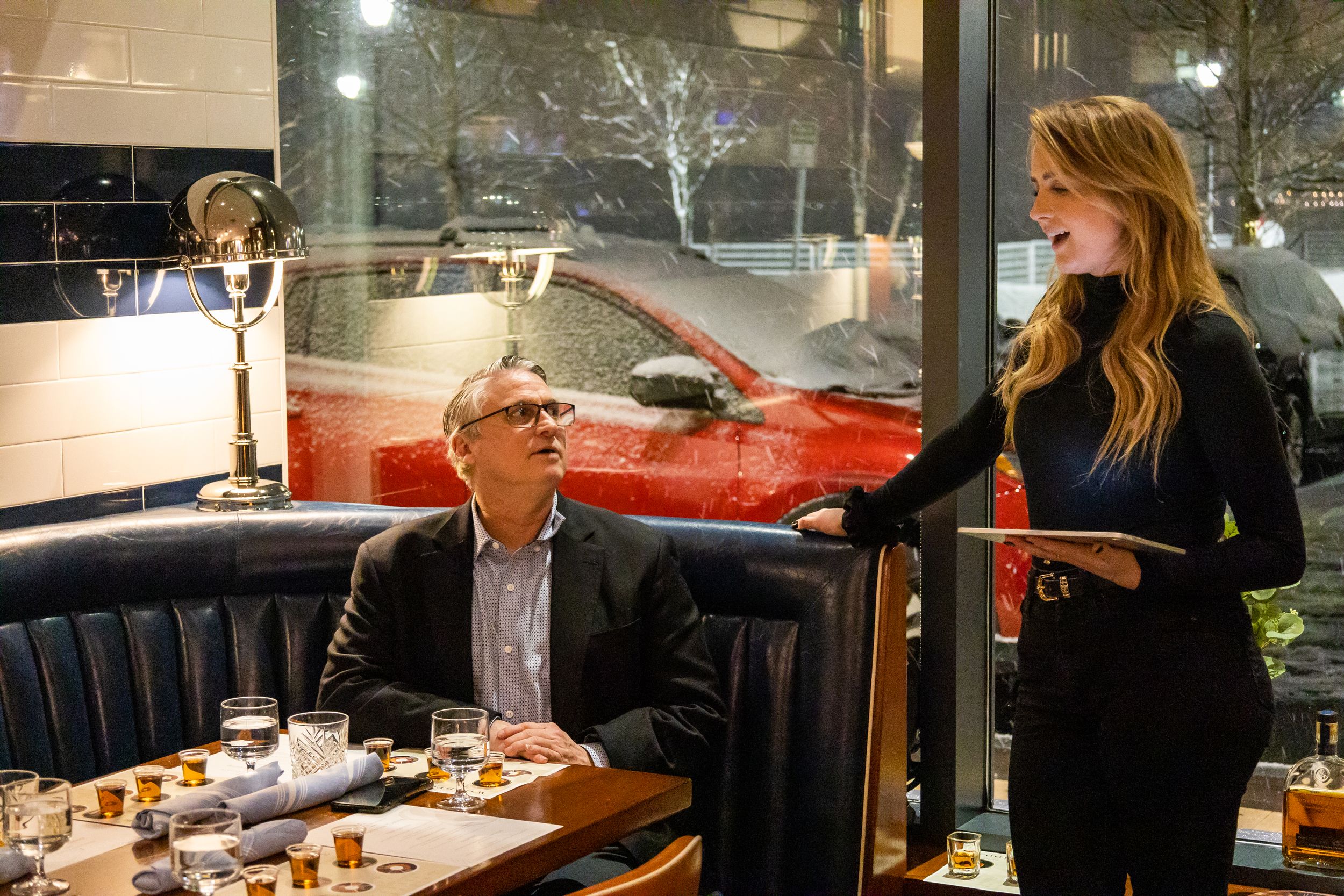 Restaurant dining scene with server attending to customers at a booth.