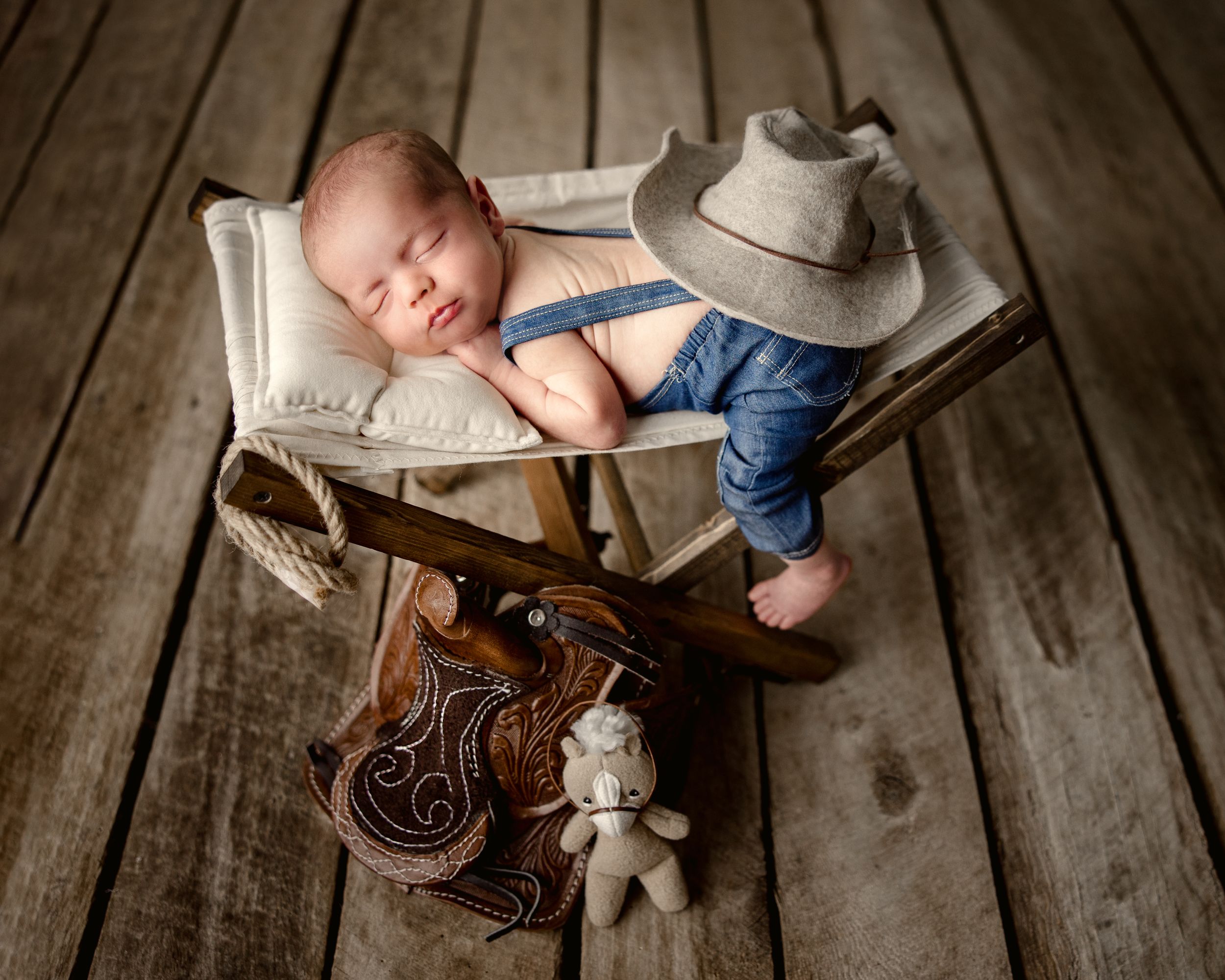 Newborn baby sleeping on wooden floor with cowboy boots and rustic props. Middle TN newborn photographer.