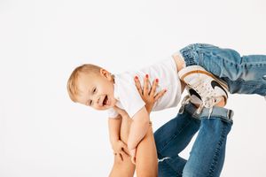 Baby in blue jeans and white shirt crawling and playing on white background in multiple action poses.