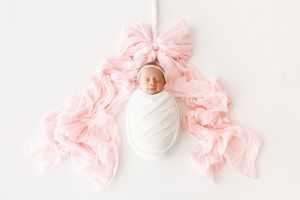 Pink hair scrunchies arranged in a row on a white background showing different textures and styles.