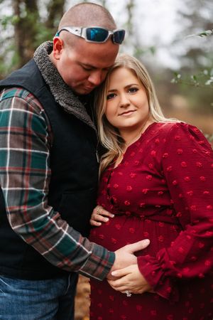 A couple embraces outdoors in autumn, with the woman wearing a burgundy sweater and the man in a plaid flannel shirt.