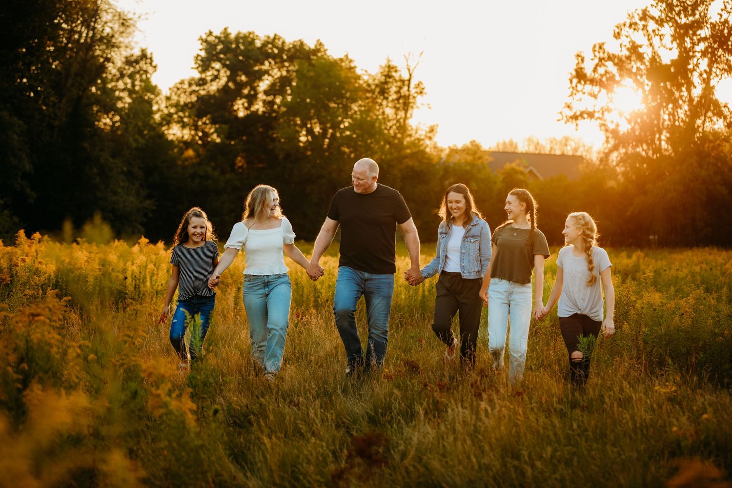Group walking together through a golden sunlit field at sunset.