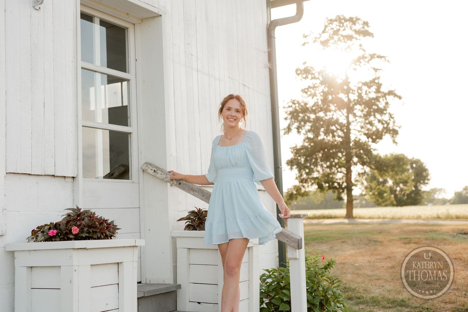 Soft afternoon sunlight illuminates a farmhouse porch scene with white architectural details.