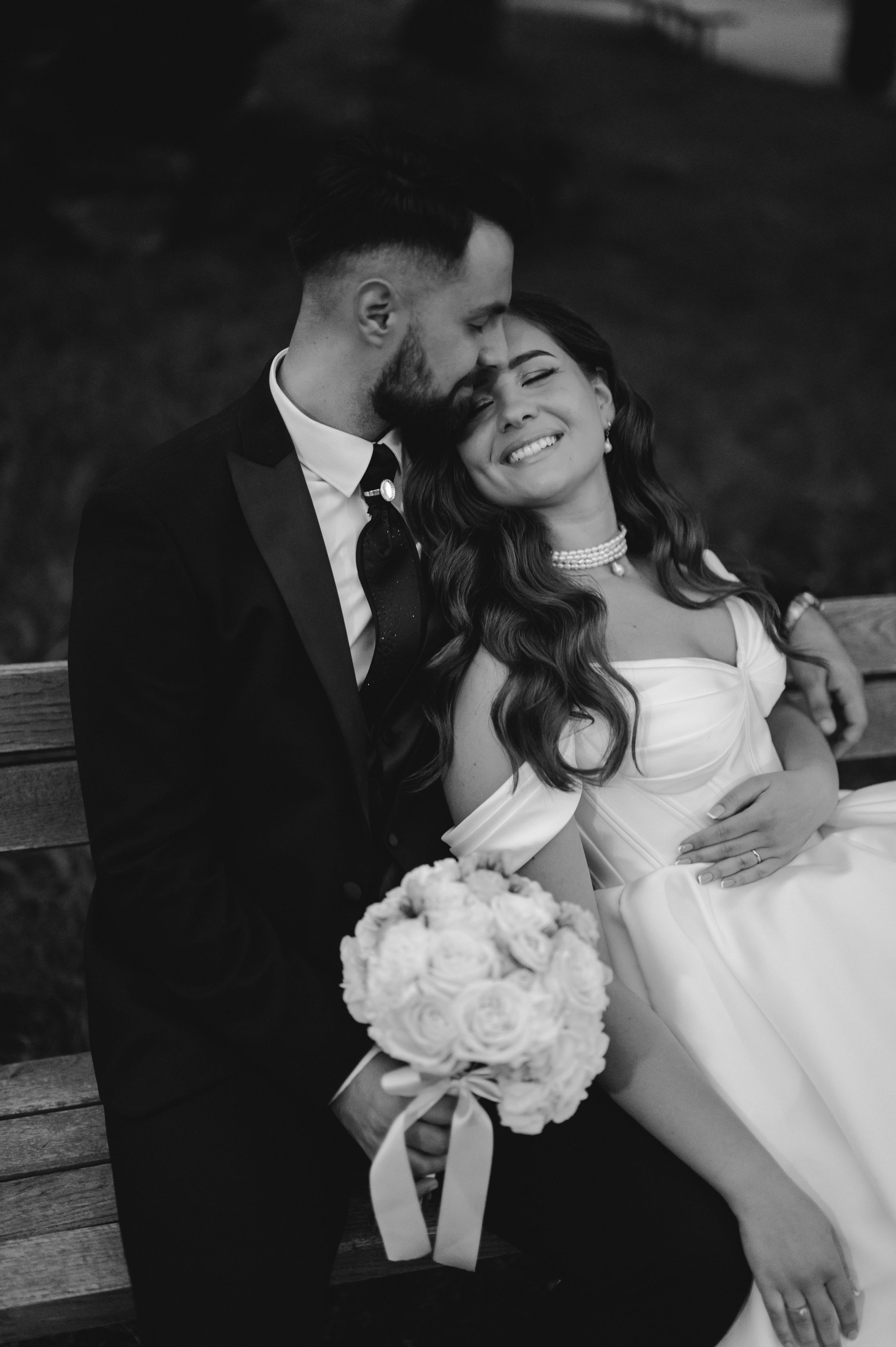 Romantic black and white wedding portraits showing tender moments with white floral bouquet.