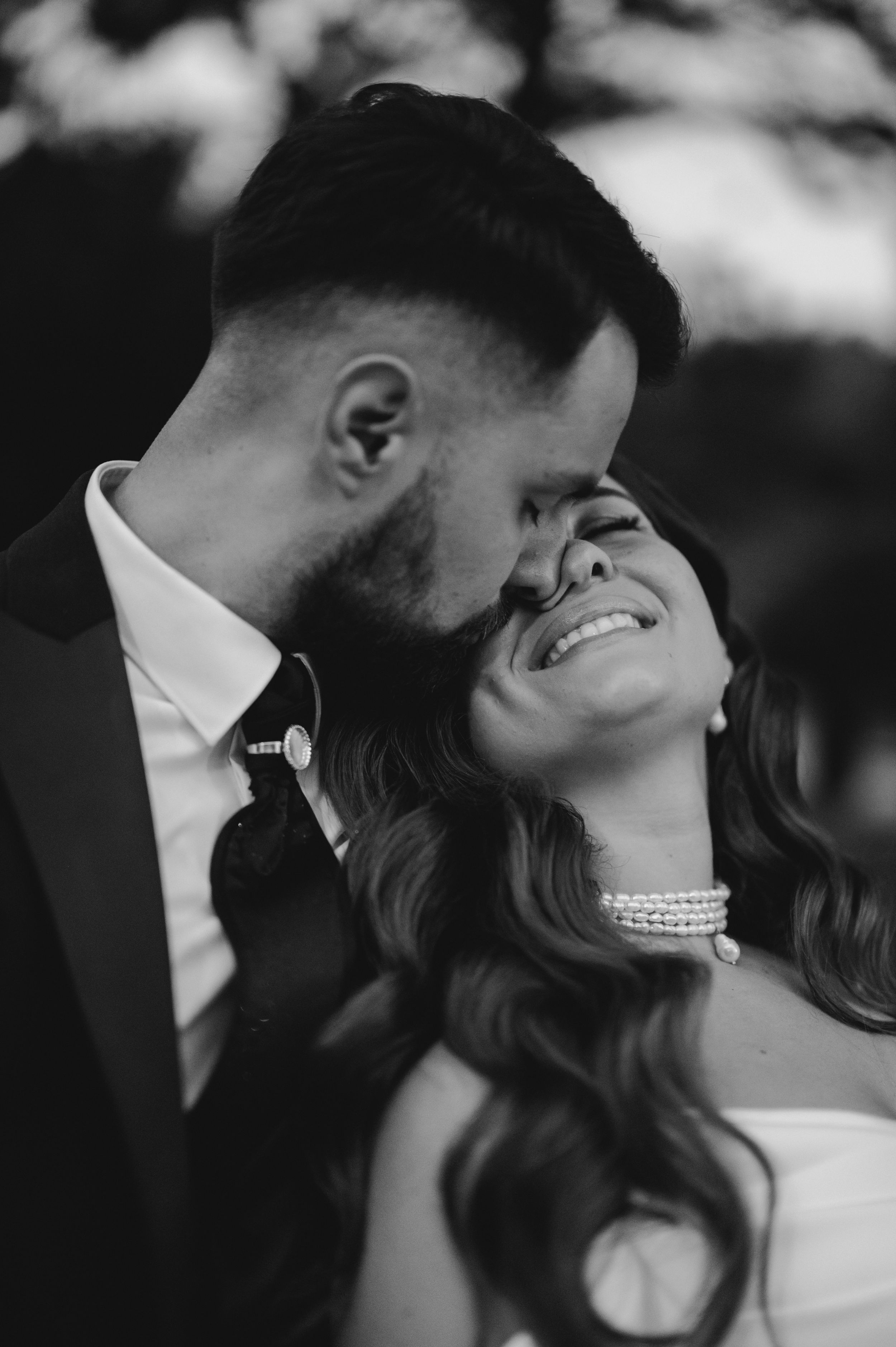 Intimate black and white close-up wedding photos showing romantic moments and pearl necklace details.