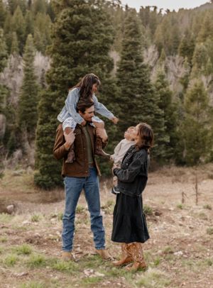 A family enjoying playful moments together in a mountainous setting with pine trees.