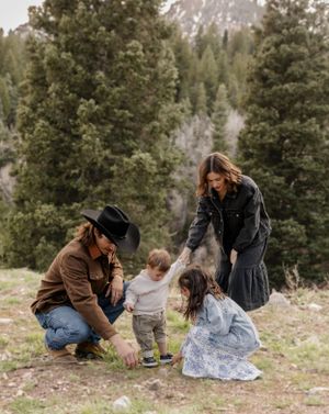 A family explores nature together in a mountain setting while dressed in casual western wear.
