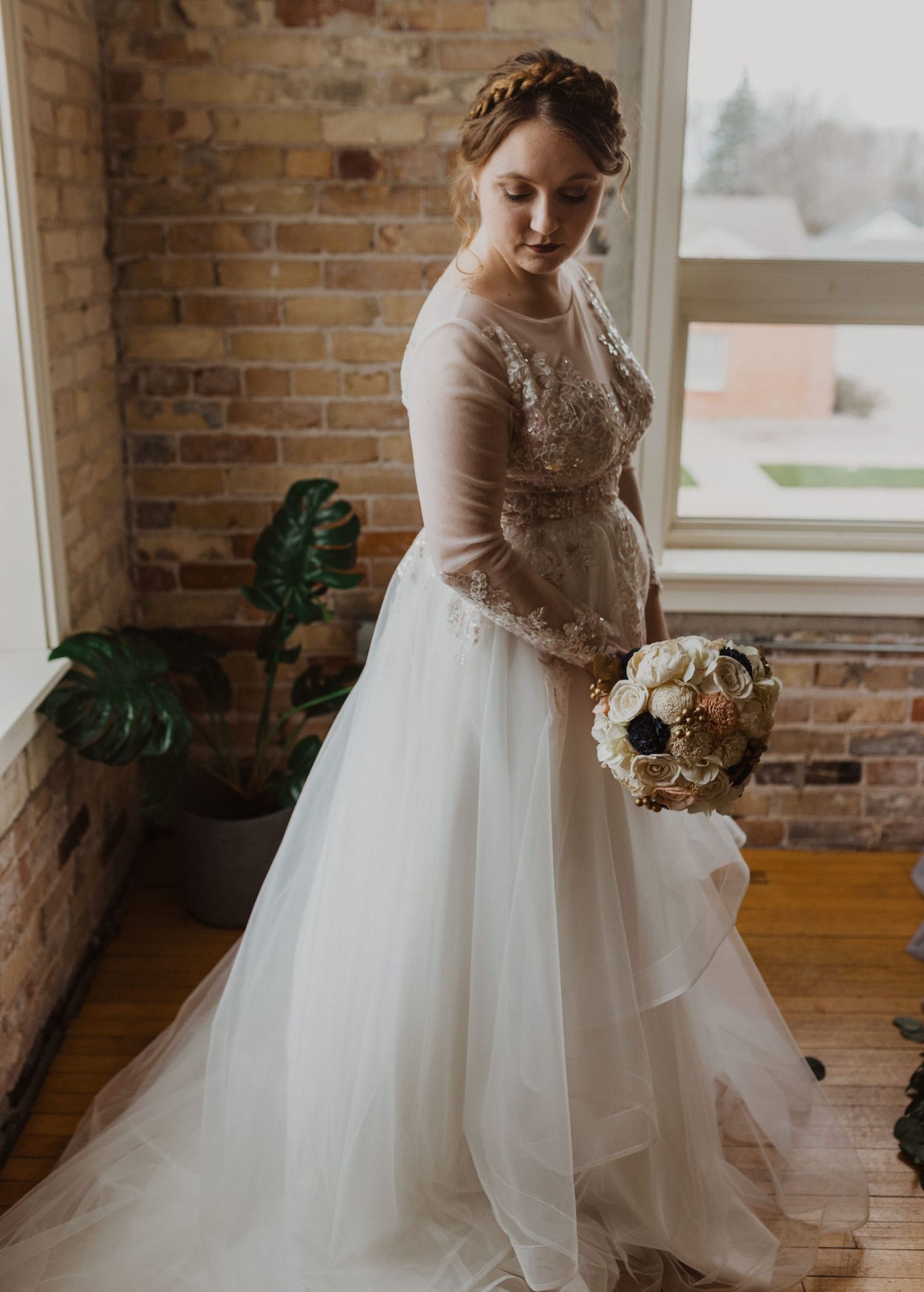 A bride in an elegant white ball gown twirls in a rustic venue with exposed brick walls.
