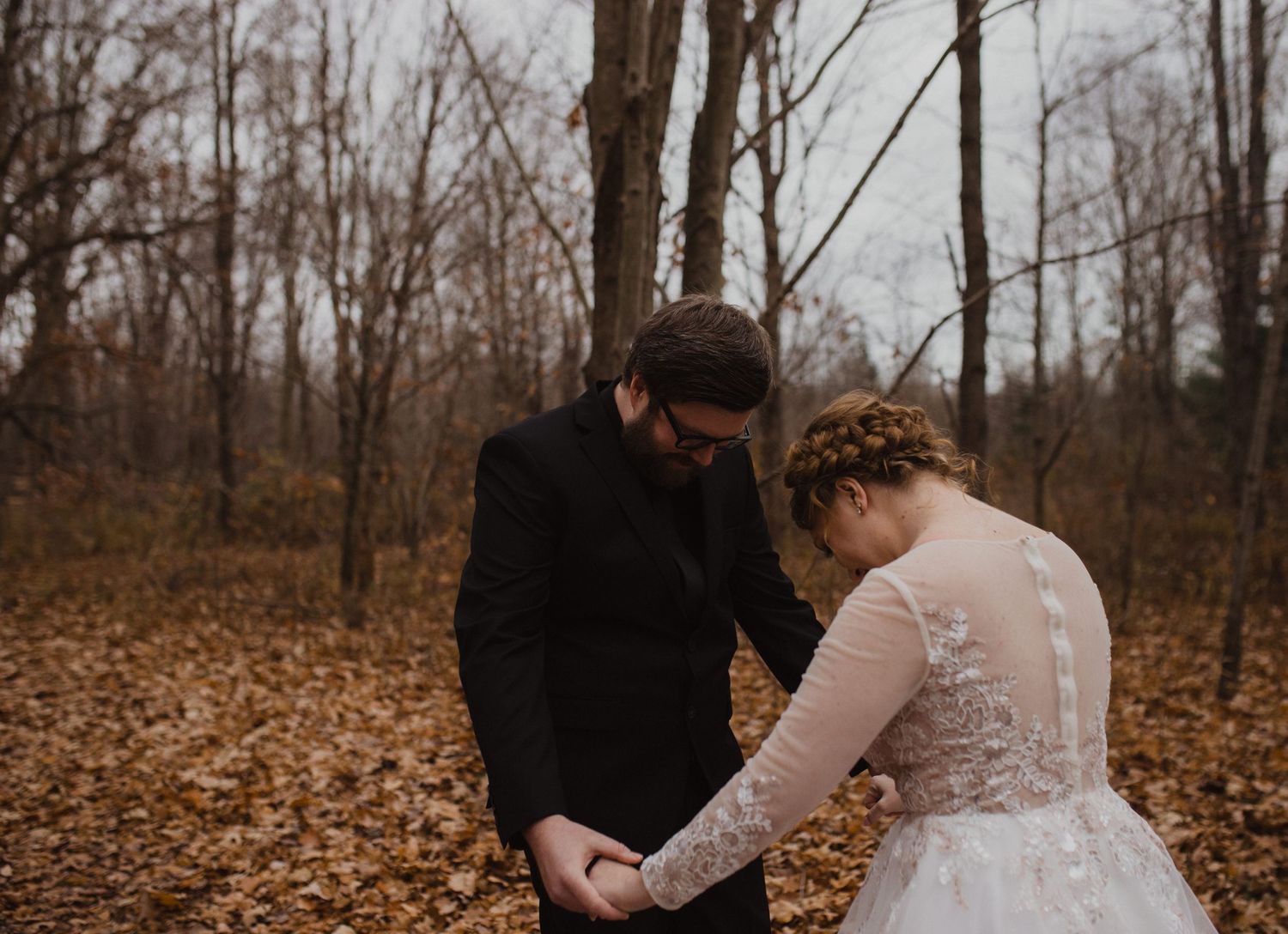 First look moment between couple in autumn woods with fallen leaves.