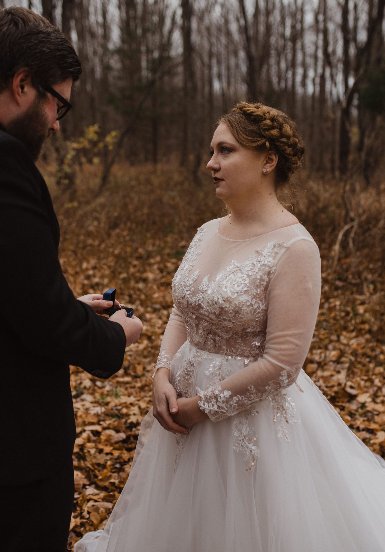 Intimate wedding ceremony exchange in wooded area with fall foliage.