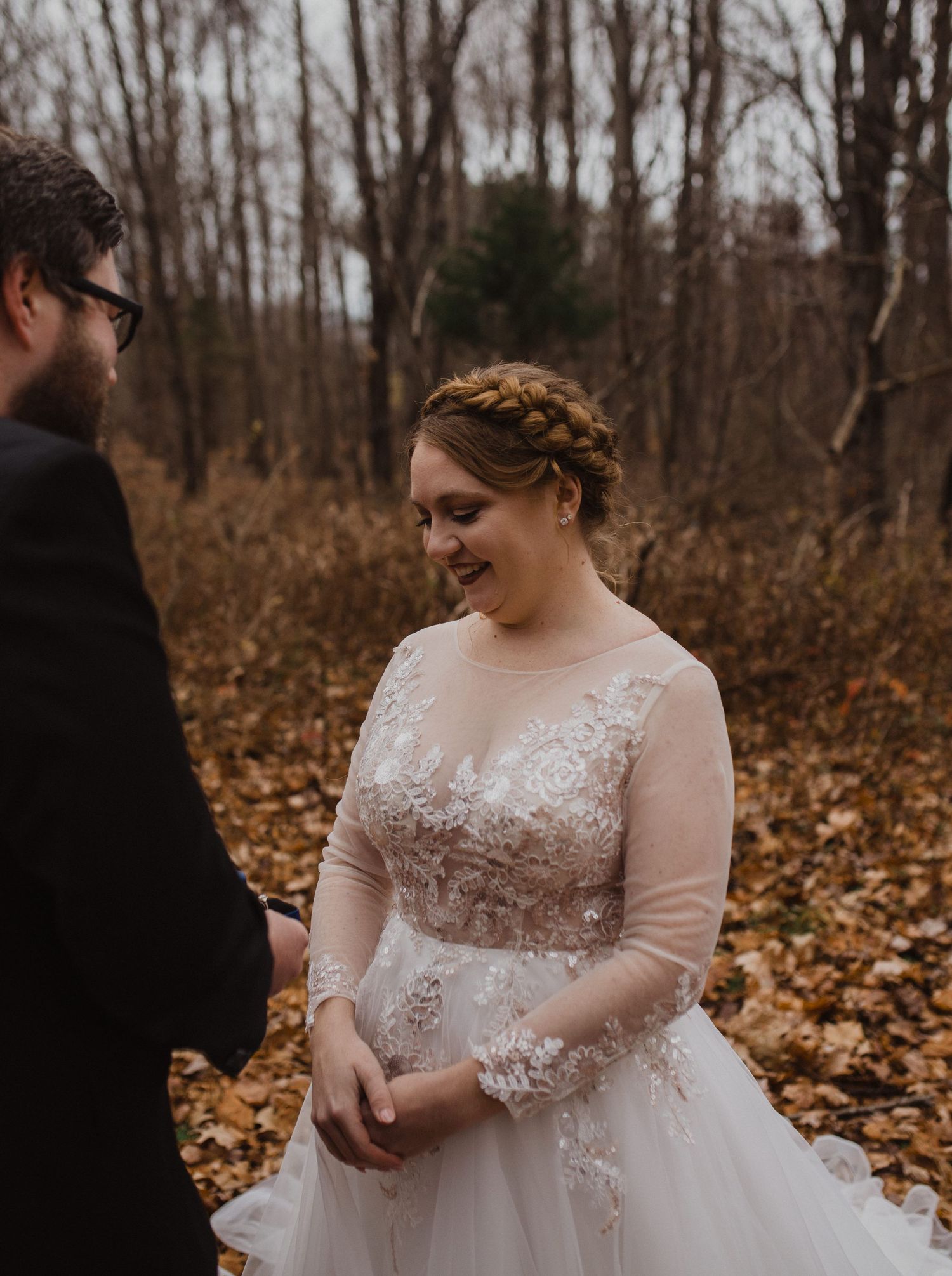 Wedding ceremony exchange in autumn forest with golden leaves on ground.