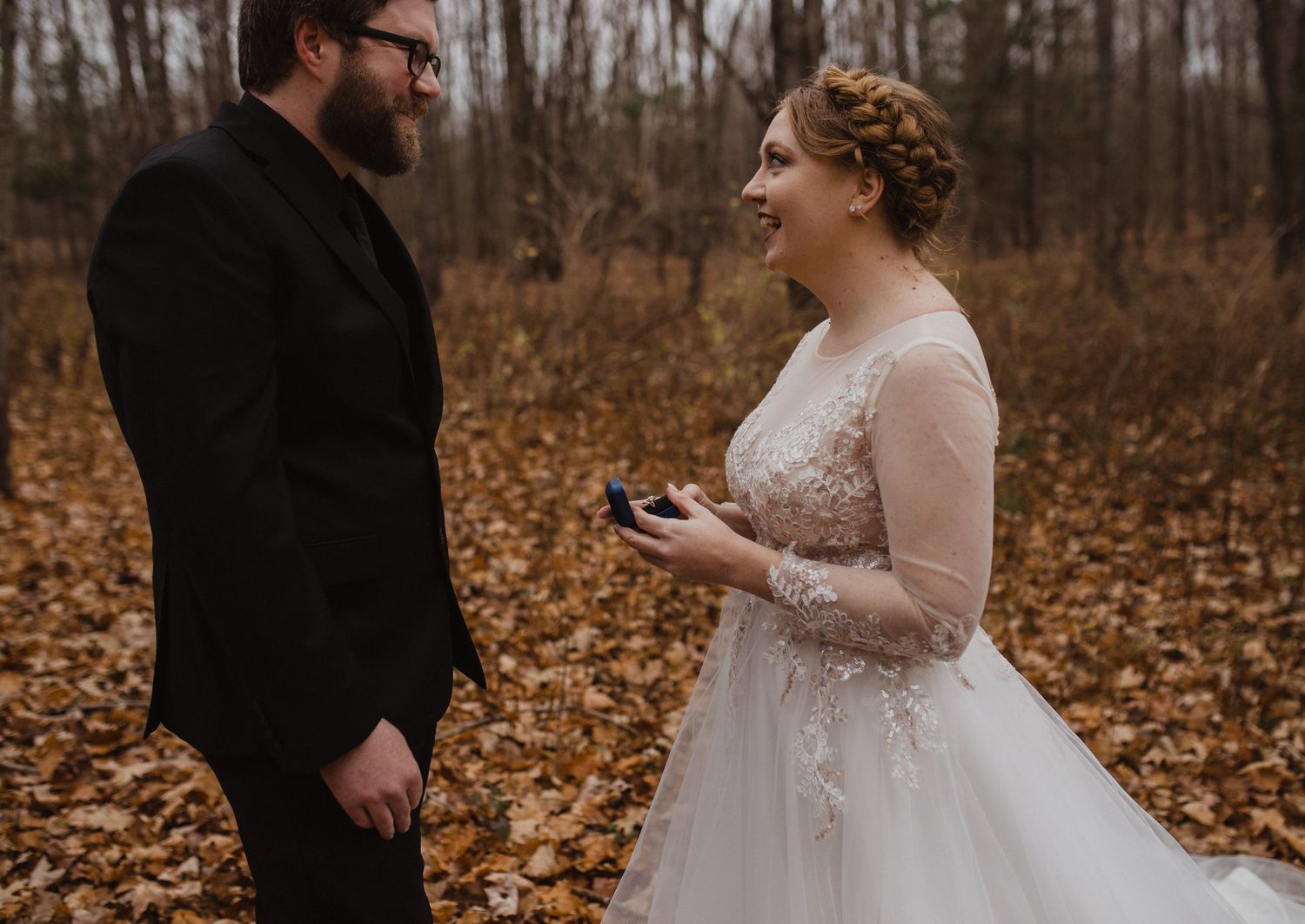 Emotional wedding ceremony moment in autumn forest setting.