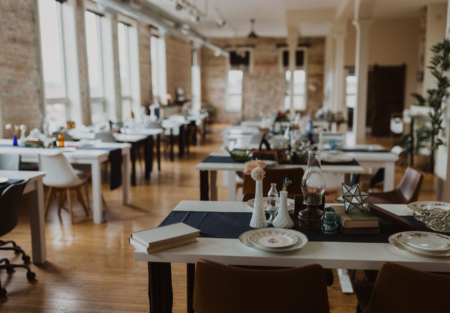 Modern event space with exposed brick walls and table settings in natural light.