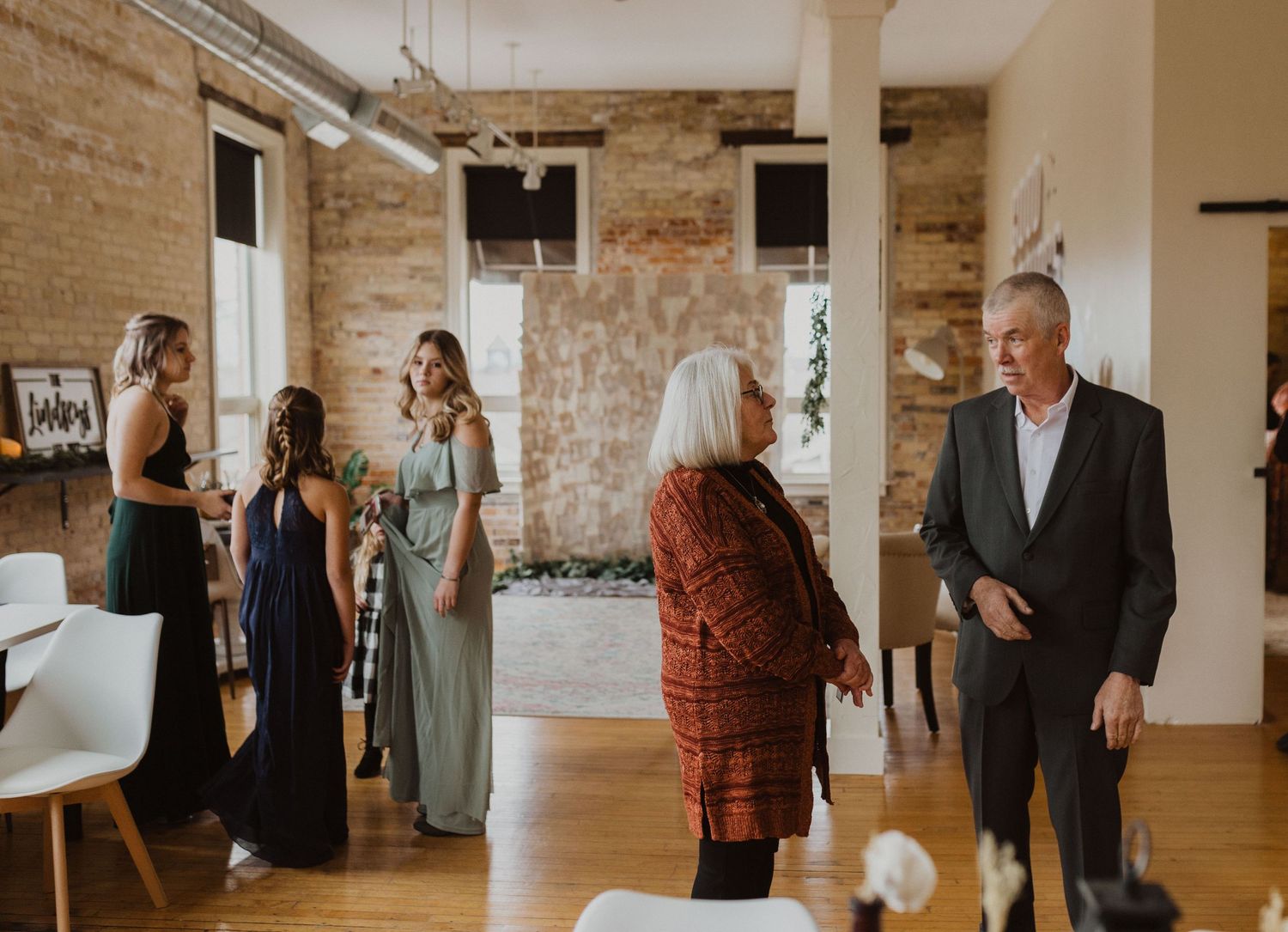 Wedding party gathering in an industrial-style venue with exposed brick walls.