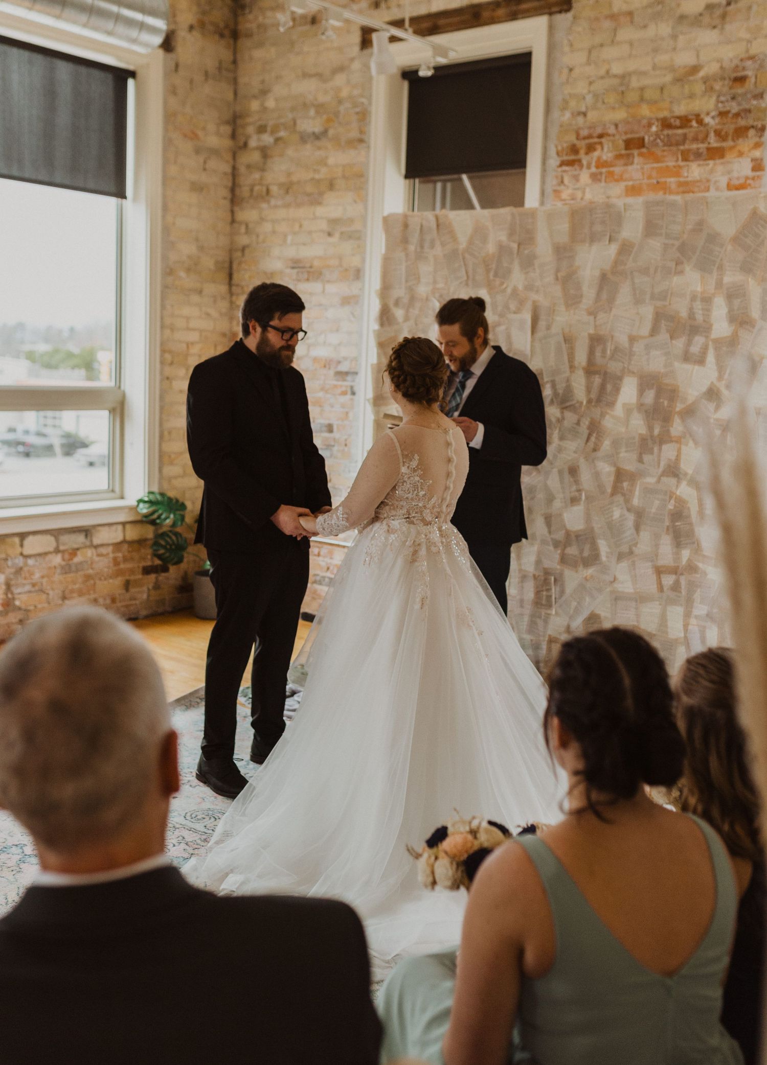 A first look wedding moment captured in an industrial brick venue with exposed walls and large windows.