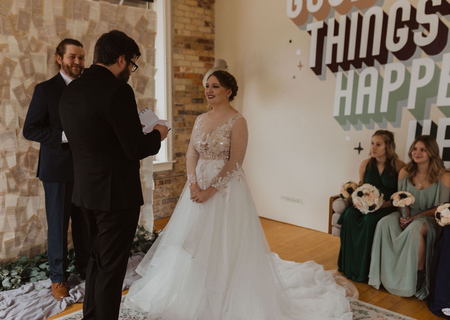 Wedding ceremony setup in a rustic brick venue with decorative signage and natural lighting.