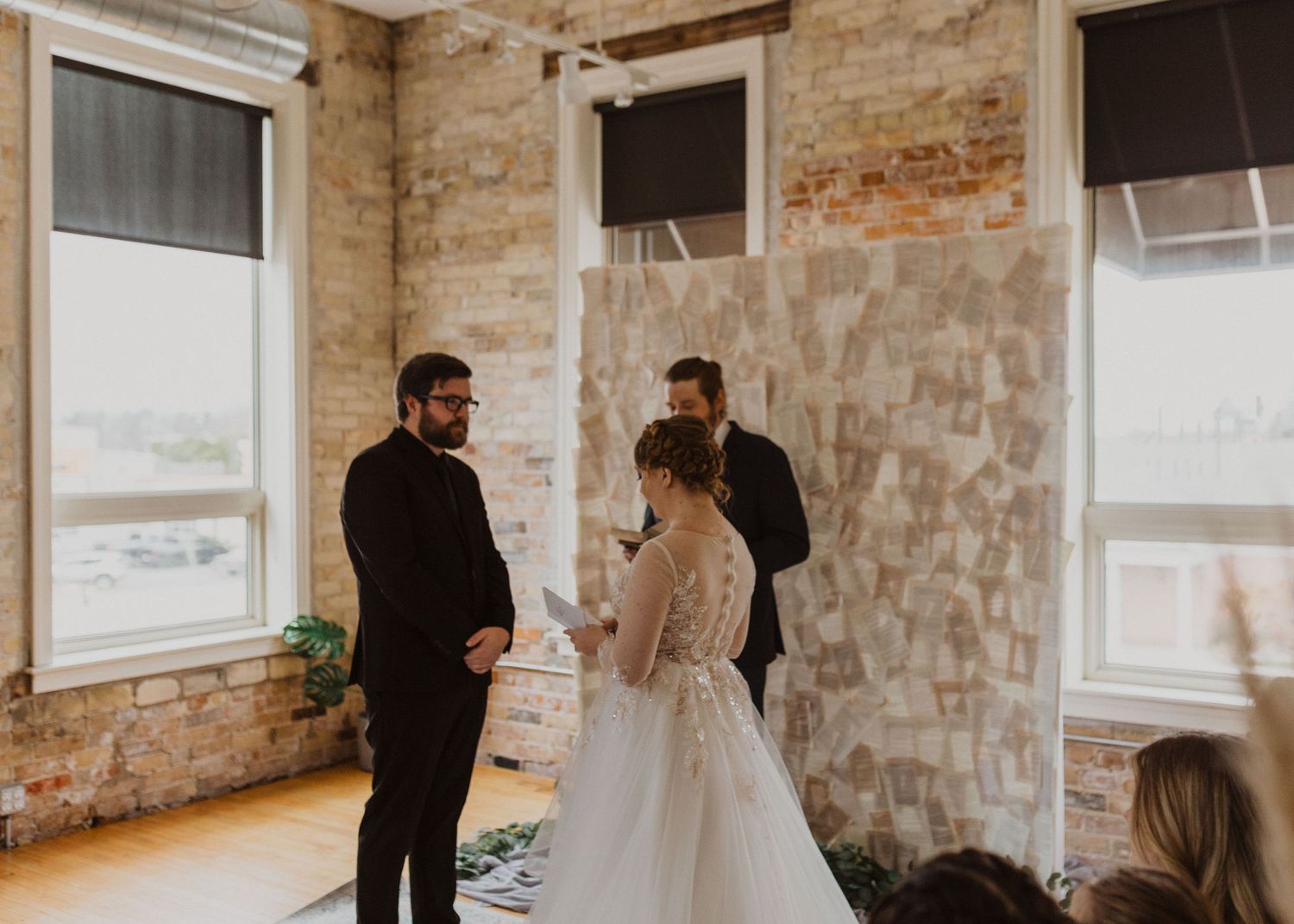 Wedding ceremony taking place in an industrial-style venue with exposed brick walls.