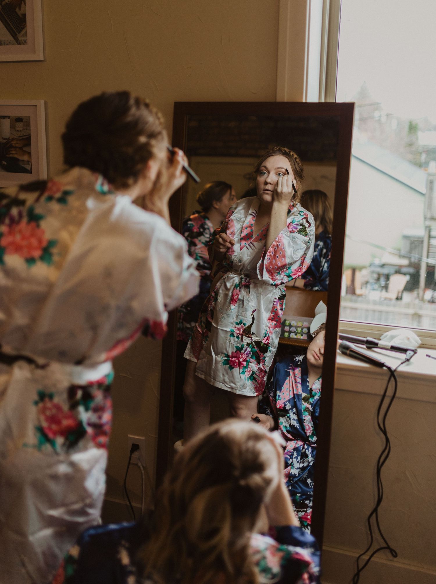 Getting ready scene with floral robes and makeup application in morning light.