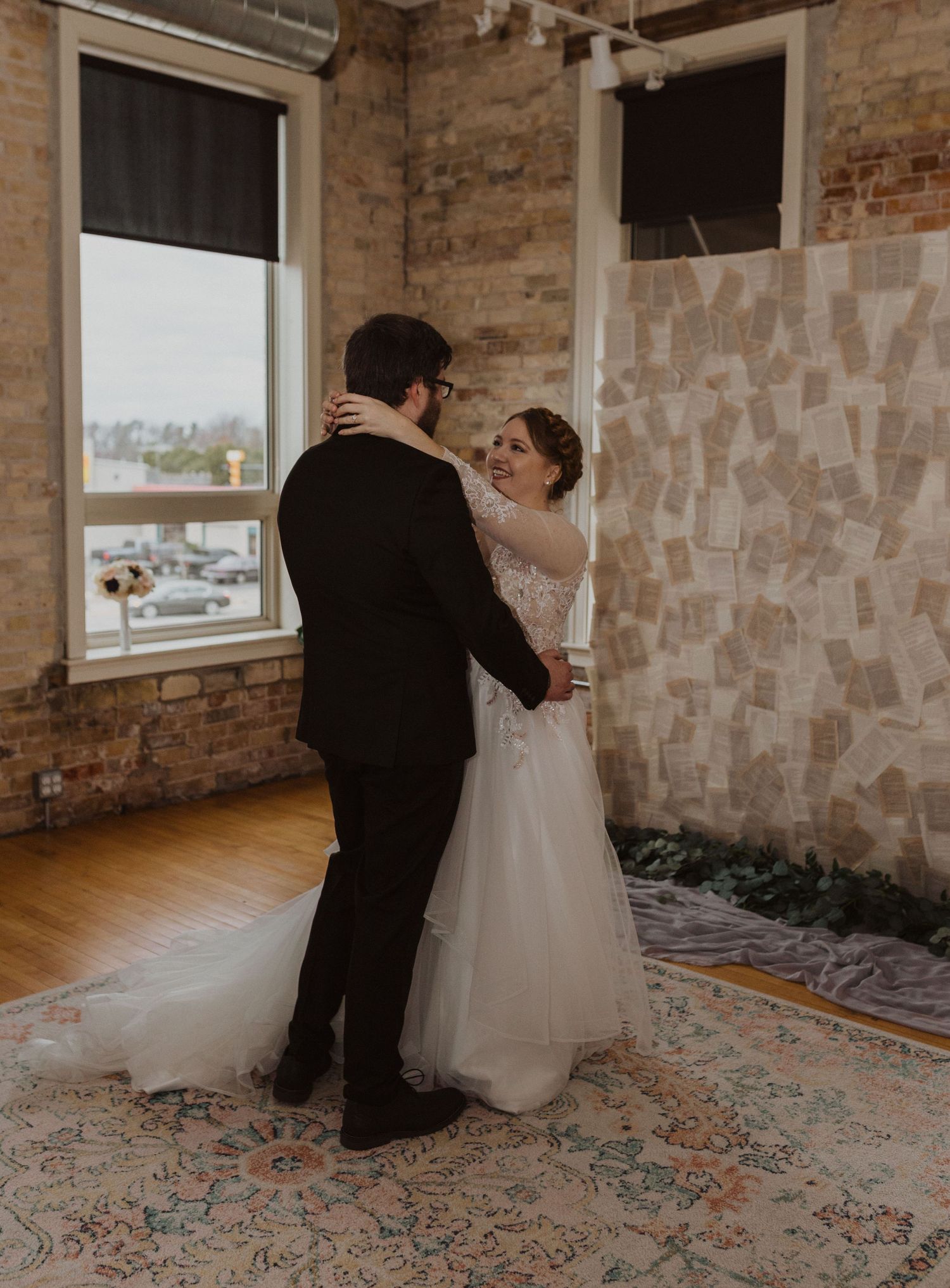 First look moment captured in a rustic venue with exposed brick walls and patterned carpet.