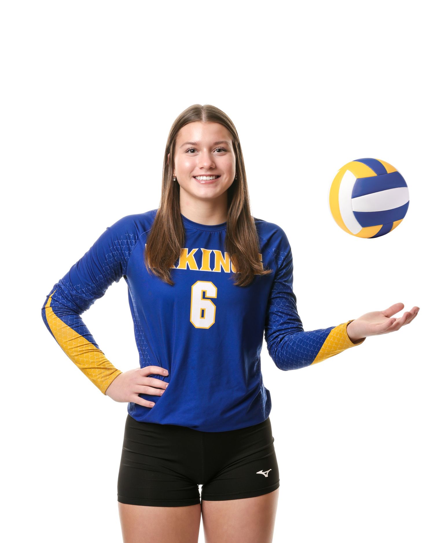 Minneota Vikings #6 volleyball player in blue jersey tossing a ball in the air.