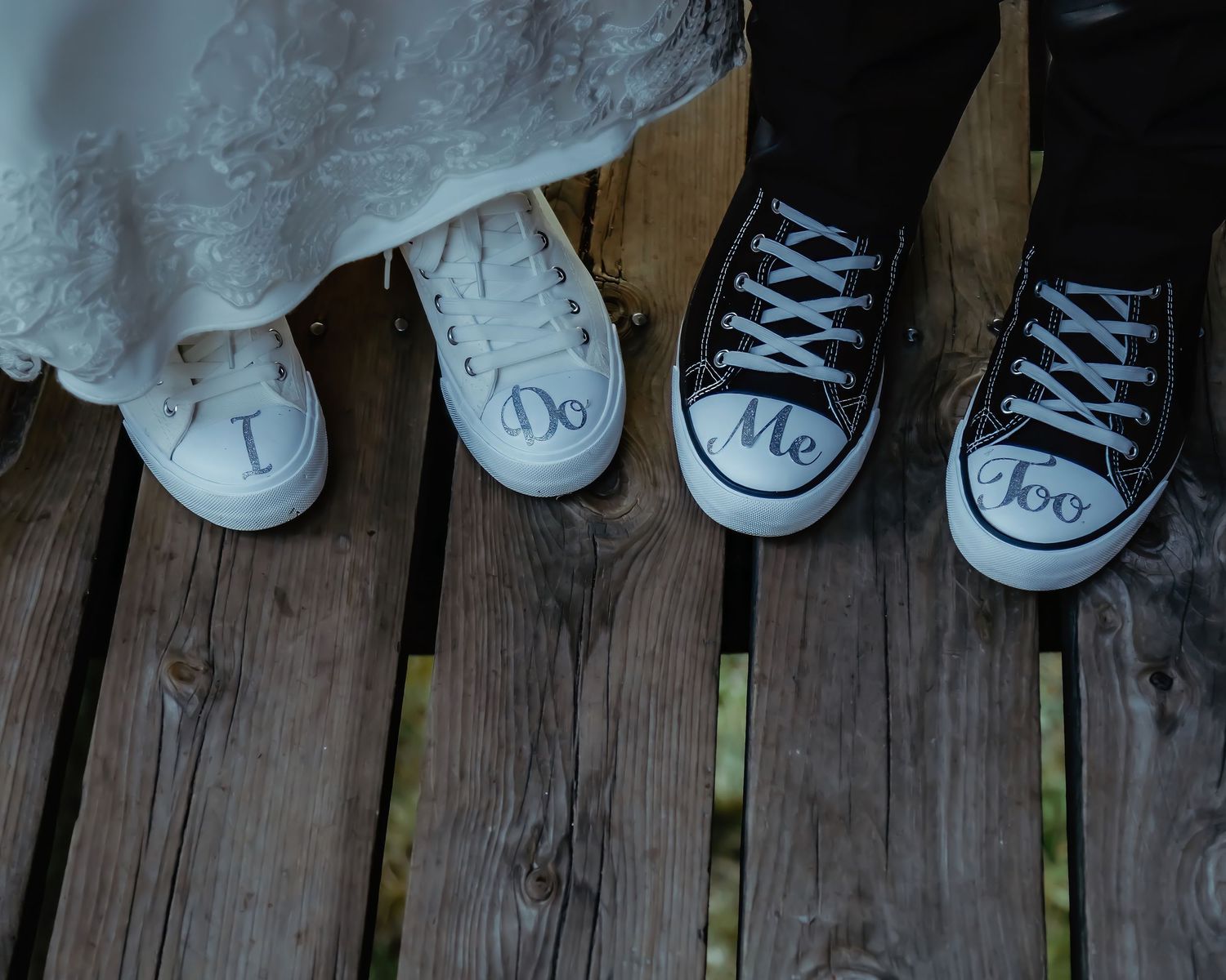 White and black wedding shoes sitting on a rustic wooden deck.