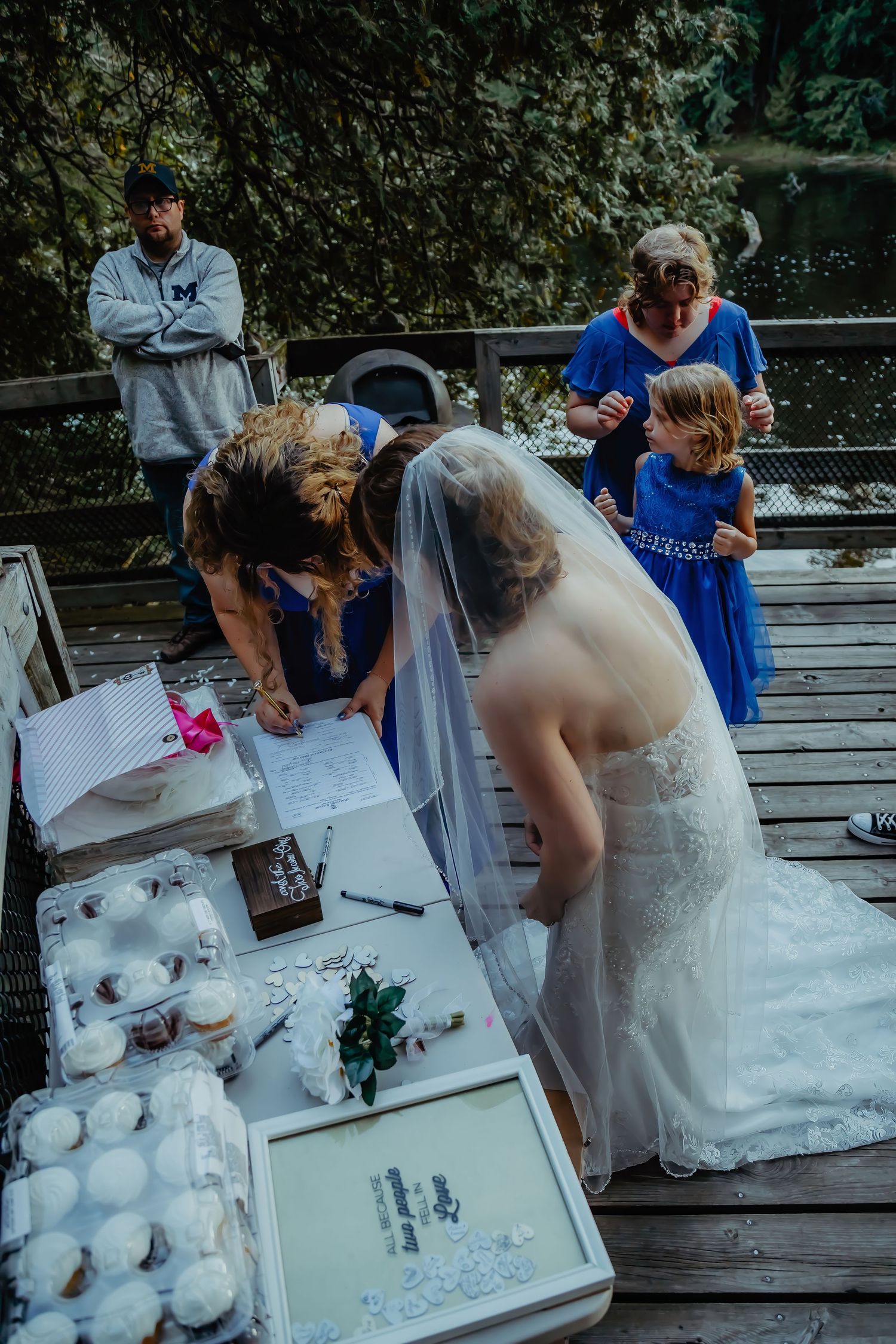 A wedding reception scene on a deck with guests looking at photo albums.