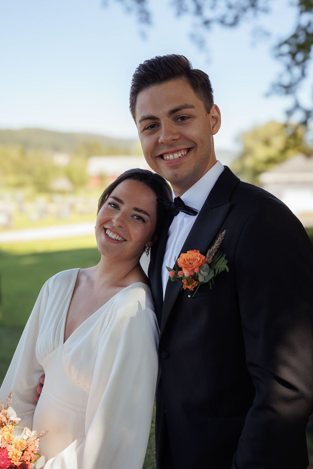A joyful wedding portrait featuring a couple in classic white dress and black tuxedo.