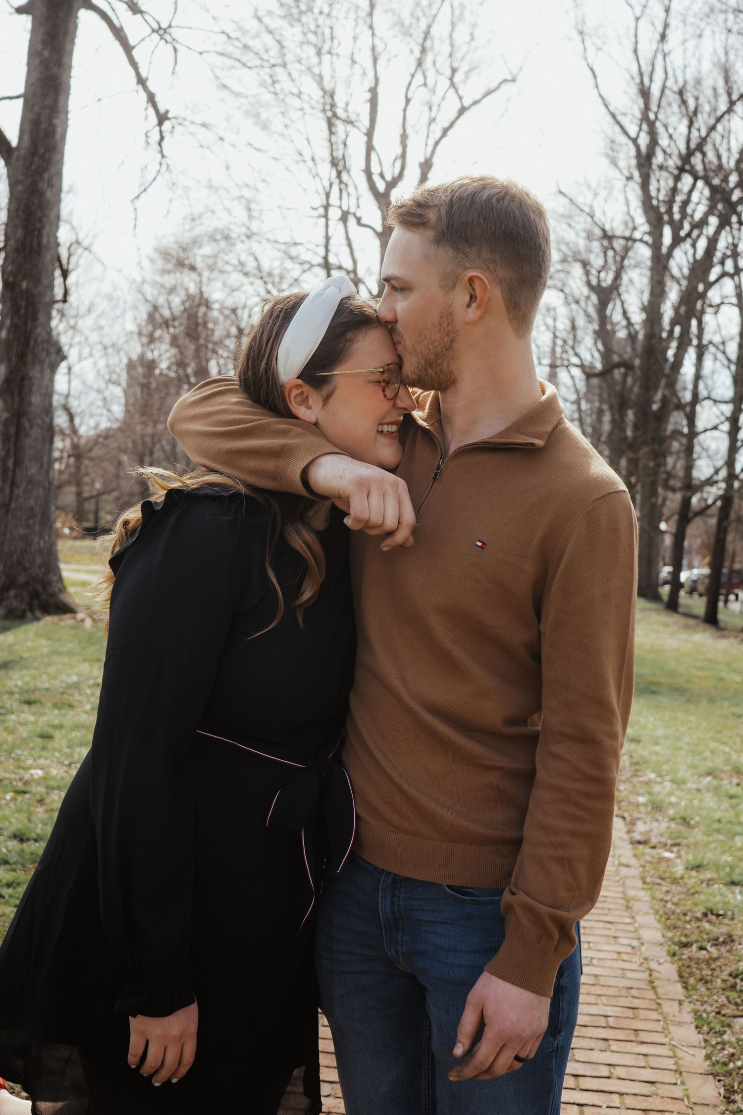 A couple embraces while sharing a joyful moment together on a brick path during autumn.
