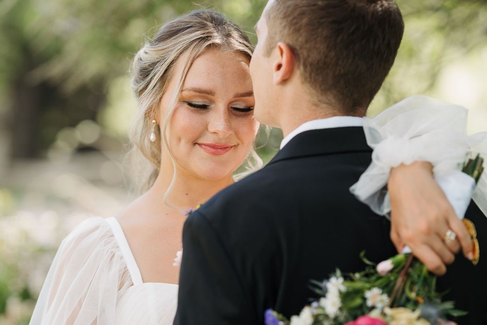 A bride and groom share an intimate moment during their wedding ceremony outdoors in natural lighting.