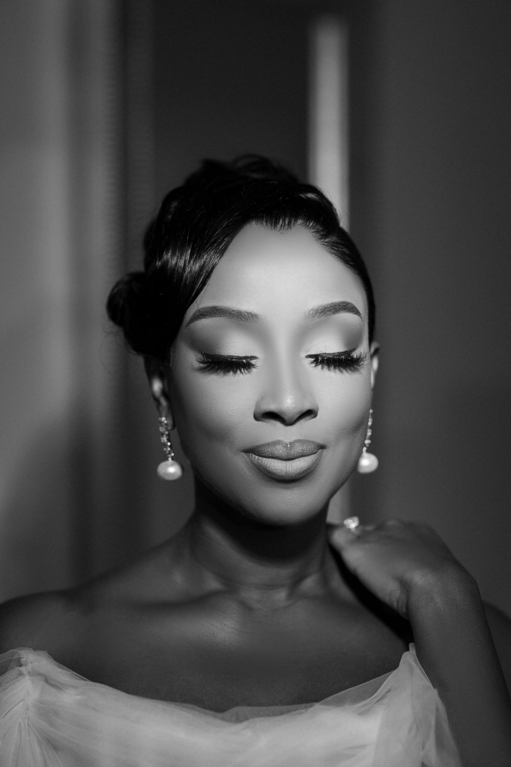 Classic black and white bridal portrait highlighting elegant makeup and pearl earrings.