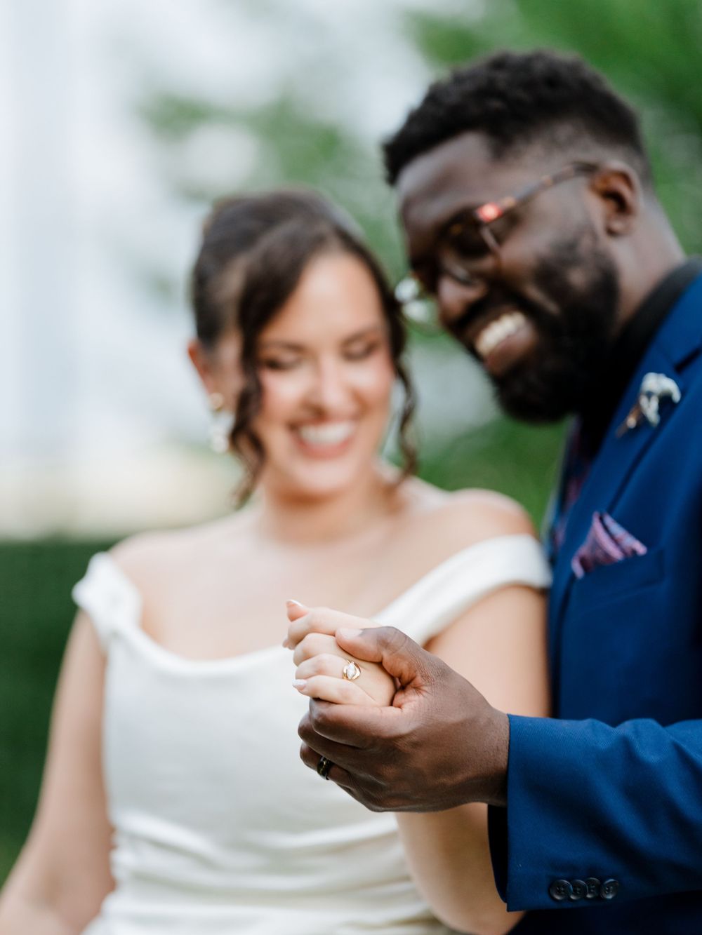 A couple exchanges wedding rings in a romantic outdoor ceremony with soft natural lighting and greenery in the background.