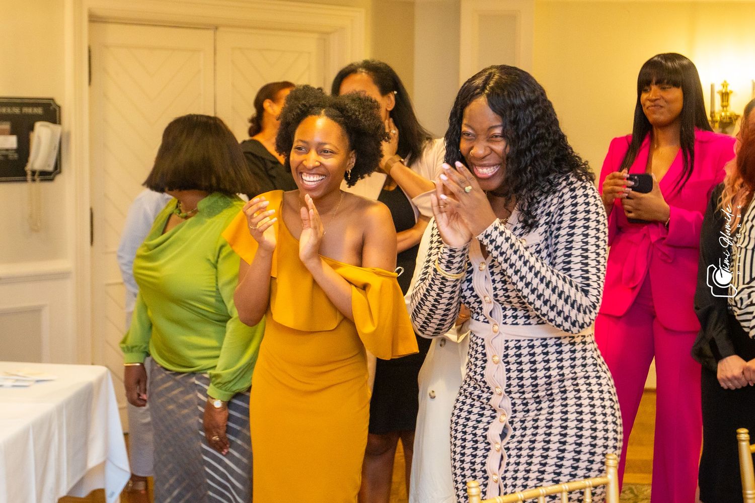 A lively celebration at an indoor event with party attendees wearing vibrant yellow, pink and patterned outfits.