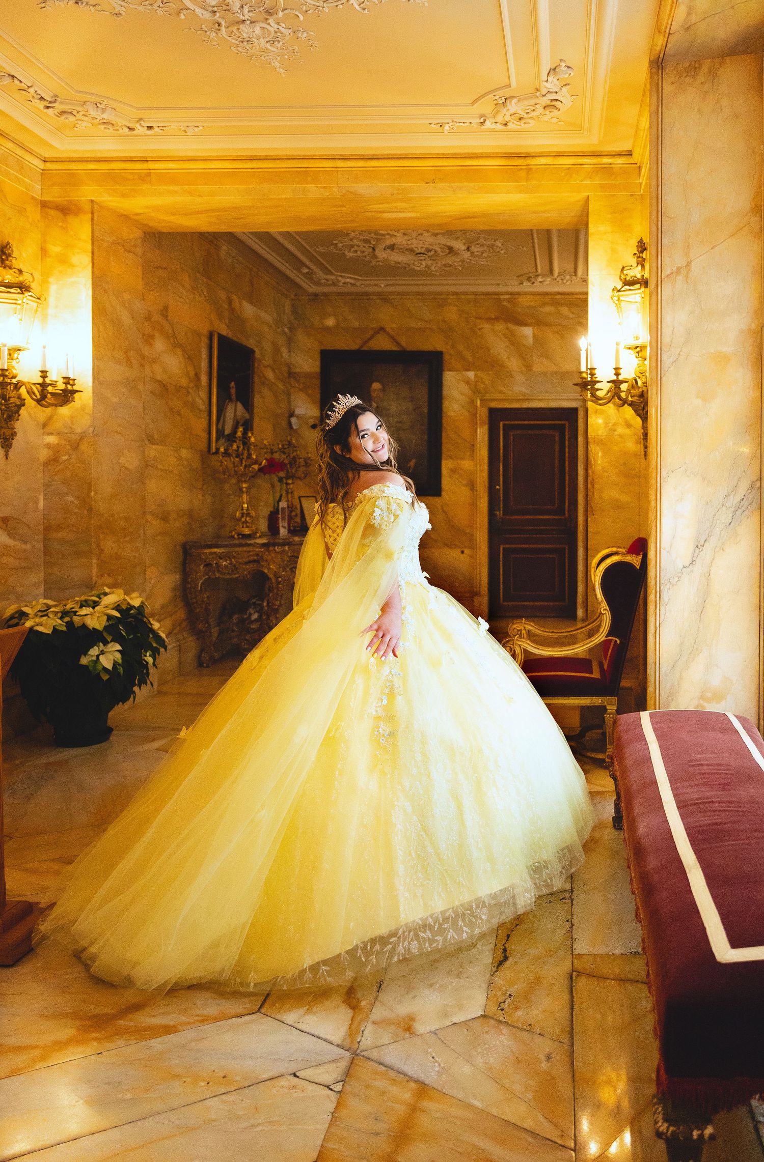 Couple descends elegant marble staircase with flowing red dress trailing behind.