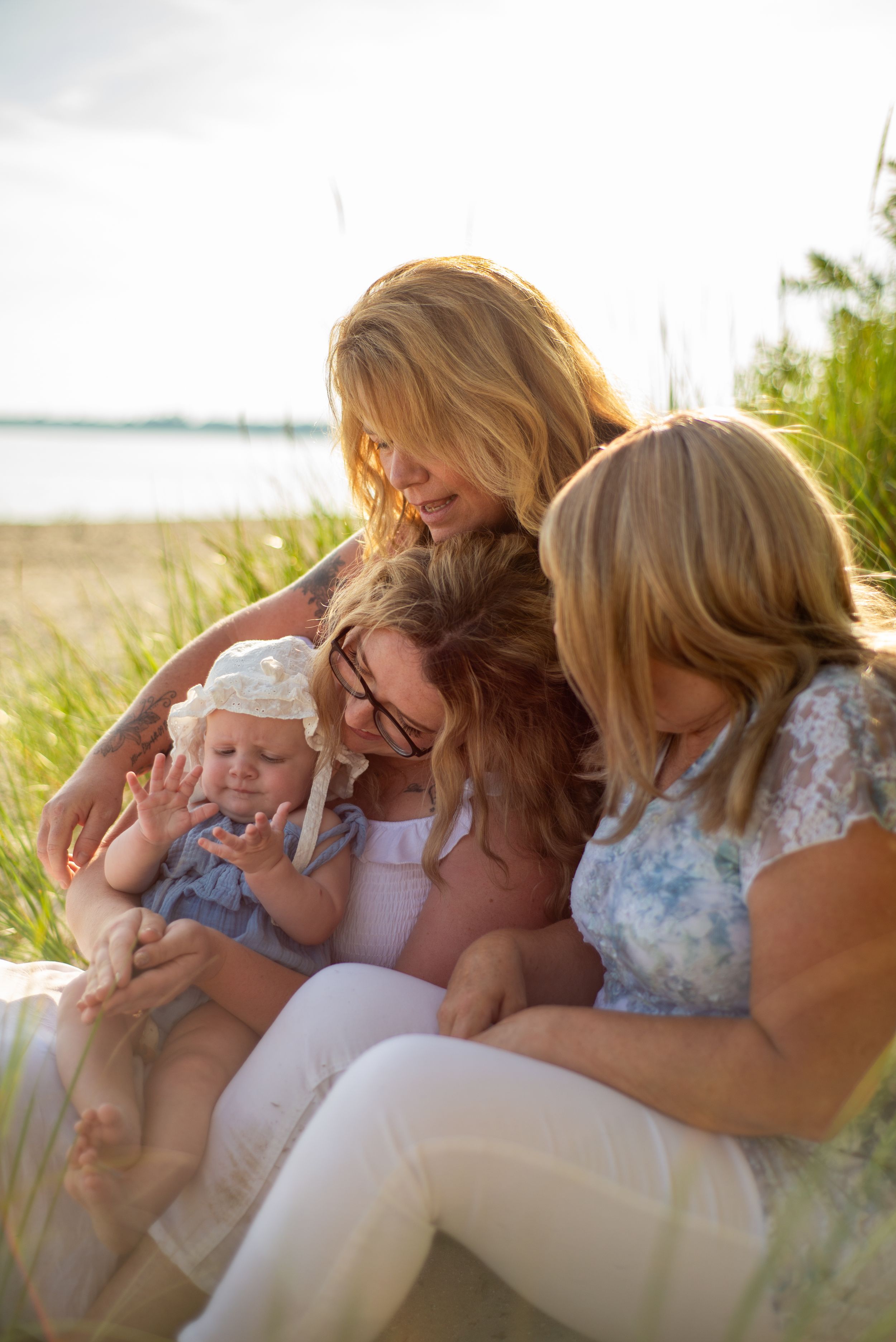 A group sits together in tall grass by the waterfront during golden hour.