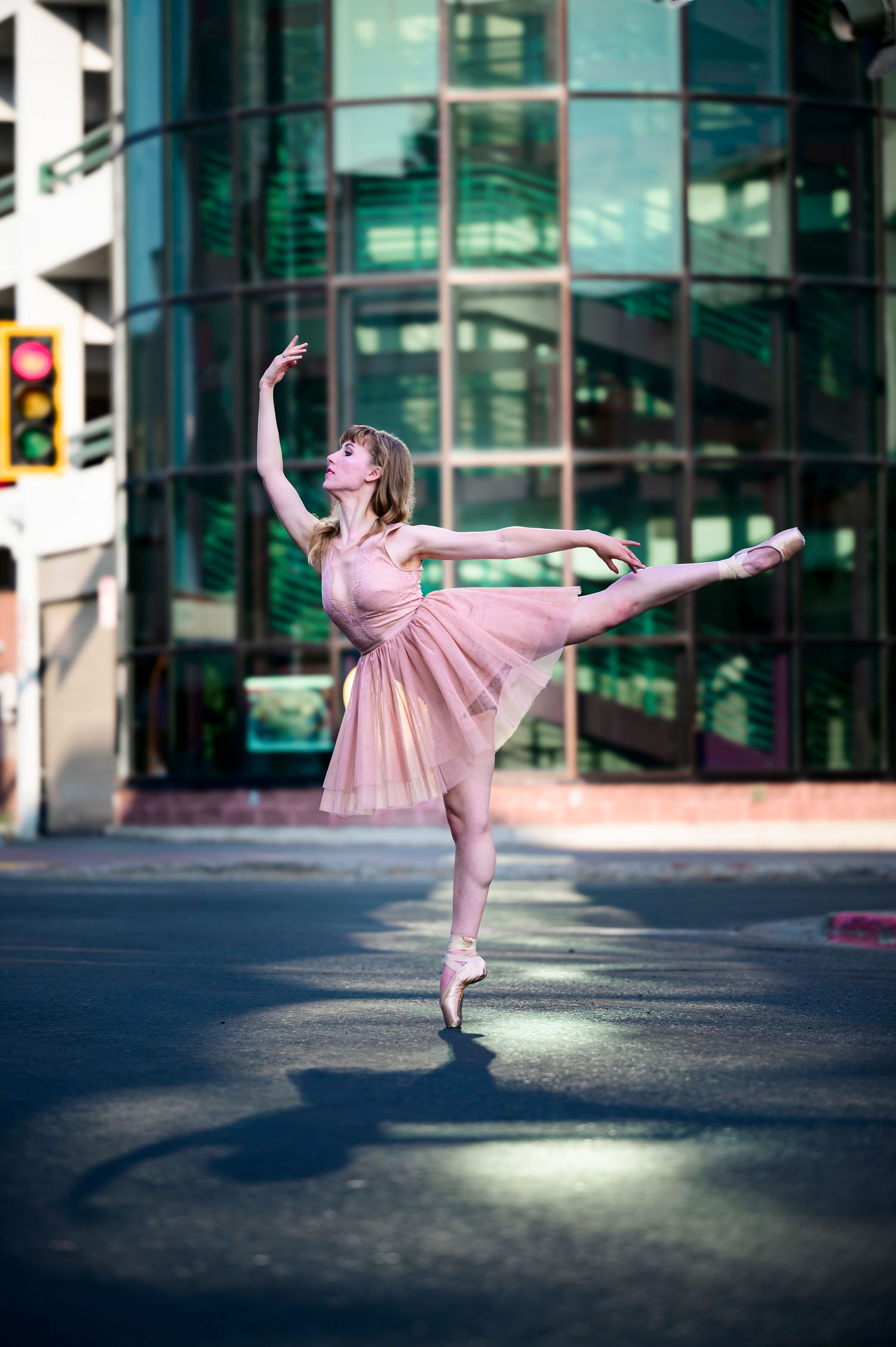 Ballet dancer in gold and red tutu performs en pointe with arms raised against black background.