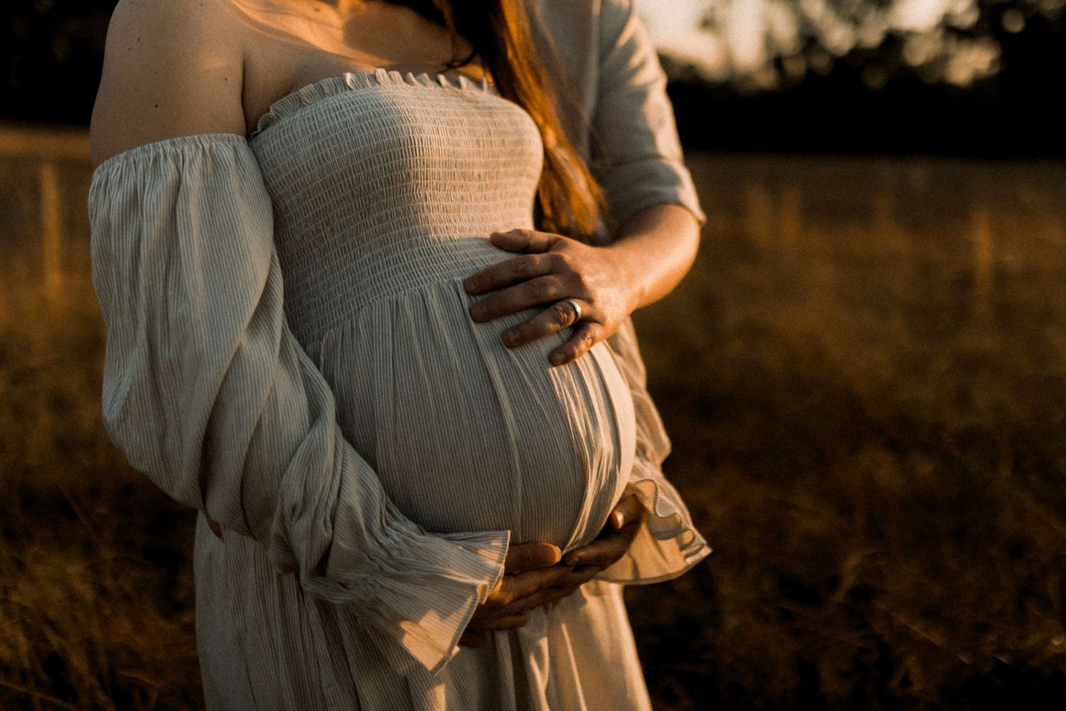 Family shares joyful moment together in golden field at sunset.