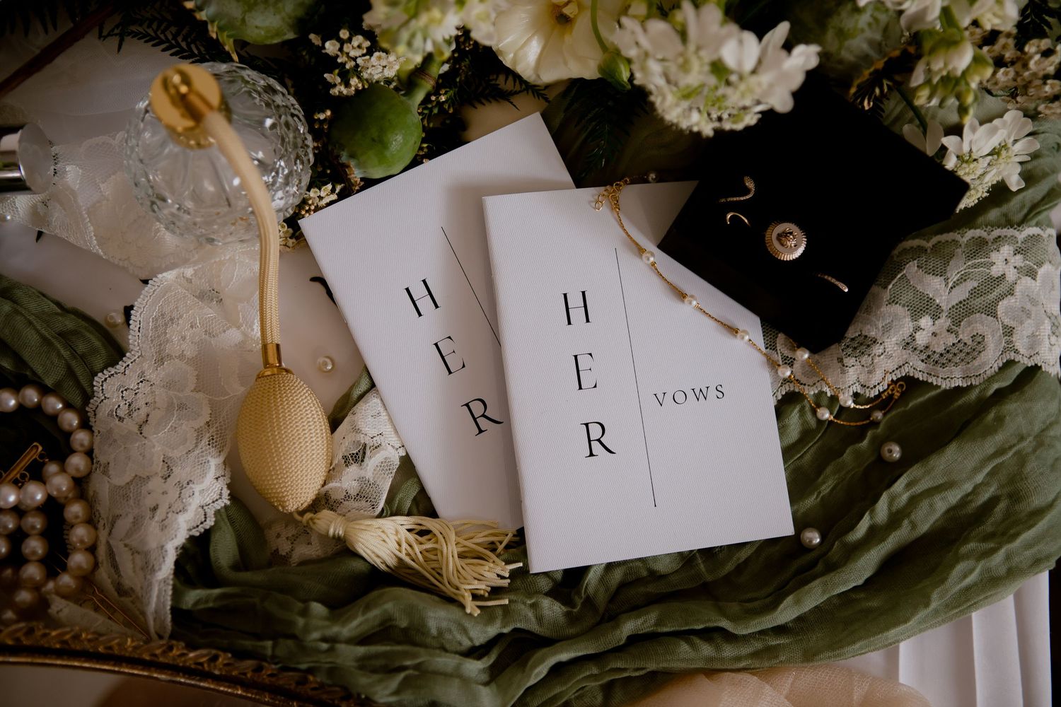 Wedding stationery cards with 'H R' text nestled among white flowers and lace decorations.