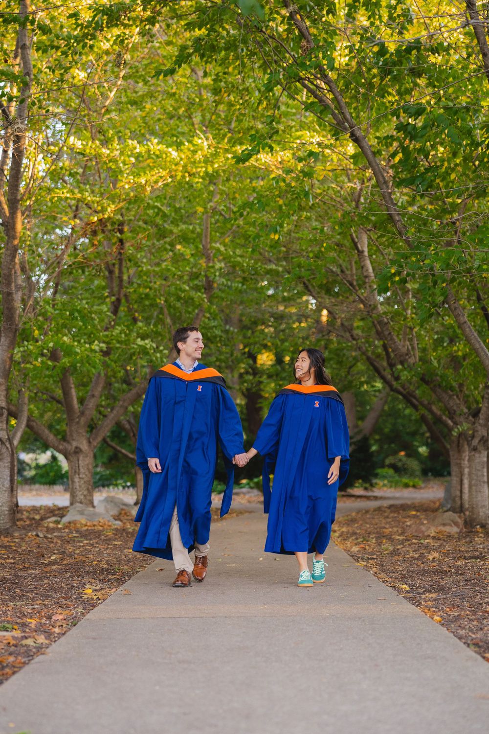 Two UIUC graduates walking together at Japan House at UIUC with masters attire