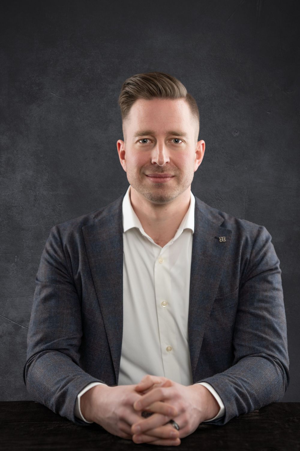 Professional studio headshot against dark textured background.
