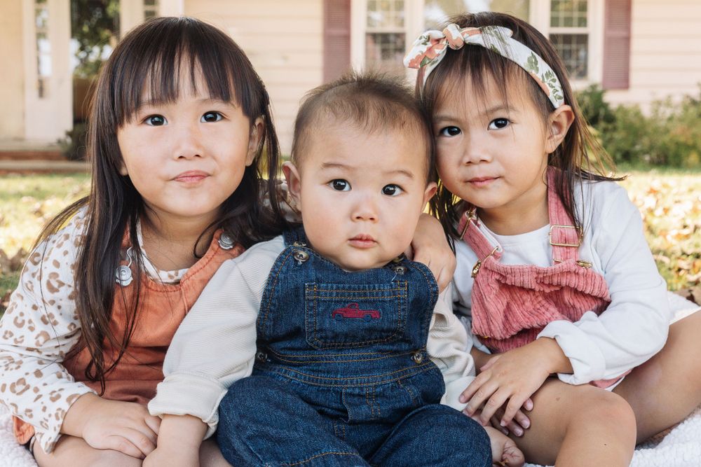 Family group portrait with young children in casual clothing outdoors.