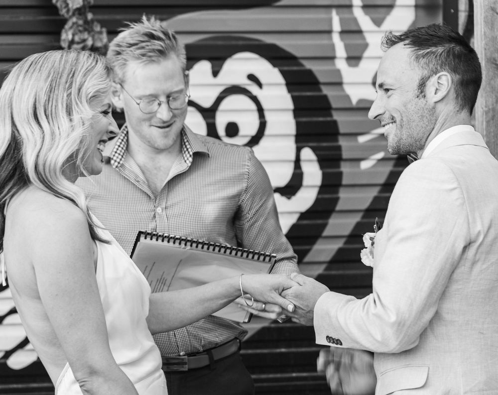 A group looking at a notebook together against a wall with street art.