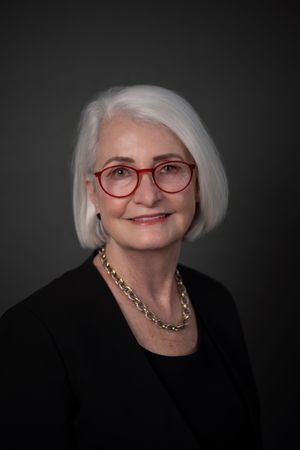 A portrait series showing an elegant older woman with white hair wearing glasses and a black top against a dark background.