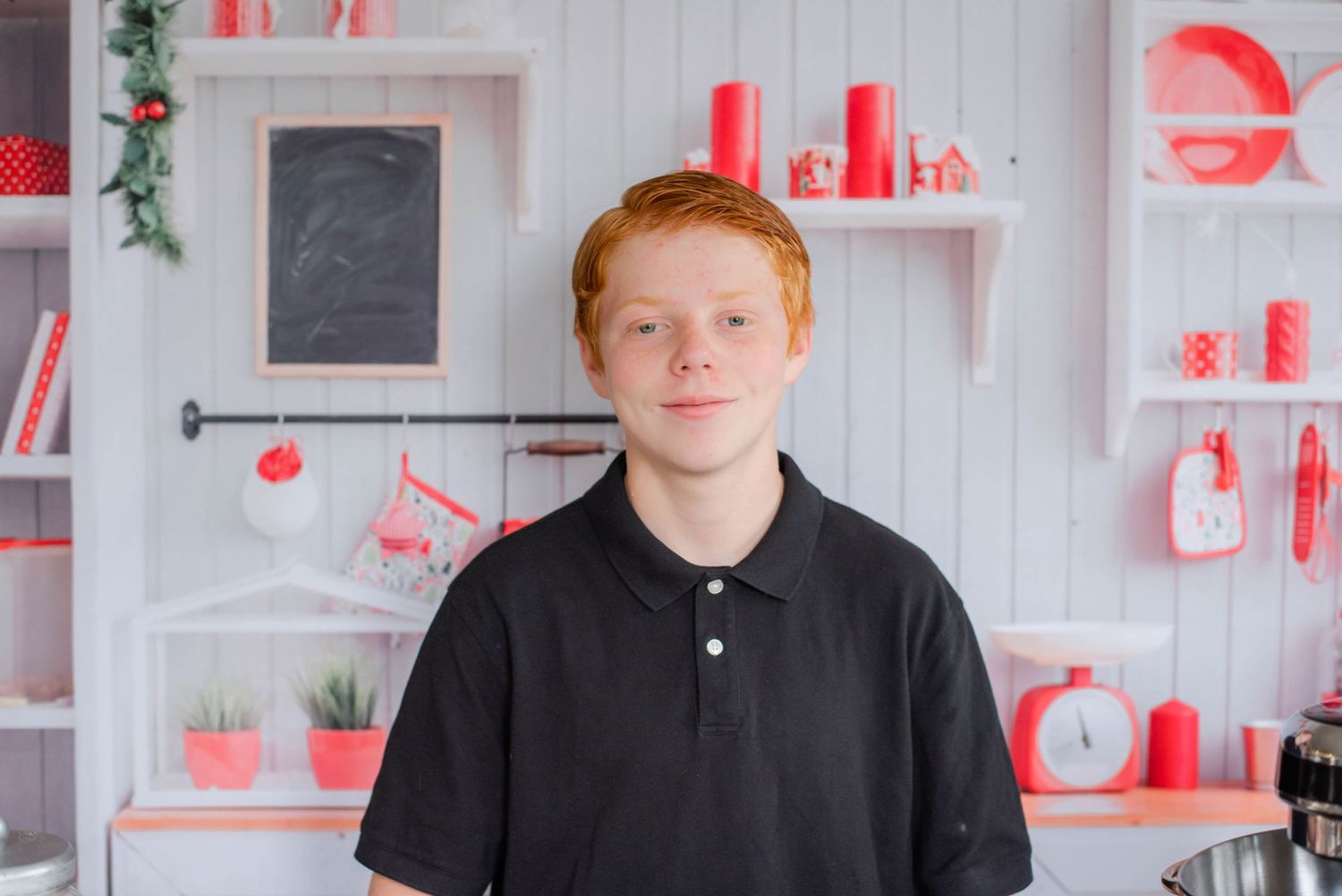 Making holiday cookies in a bright white kitchen with red accents and decorative shelving.