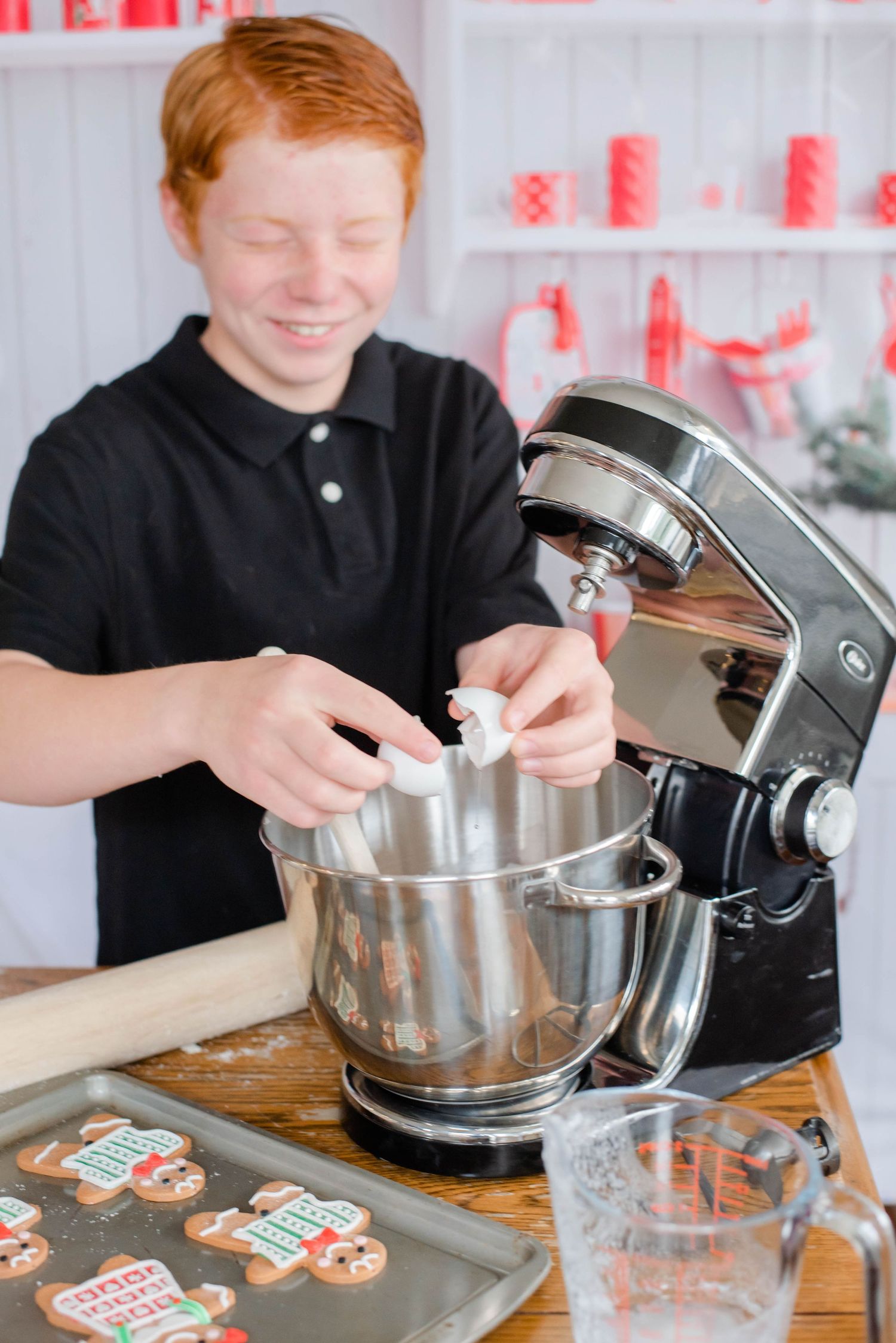 Holiday baking process with stand mixer and decorated cookies on wooden counter.