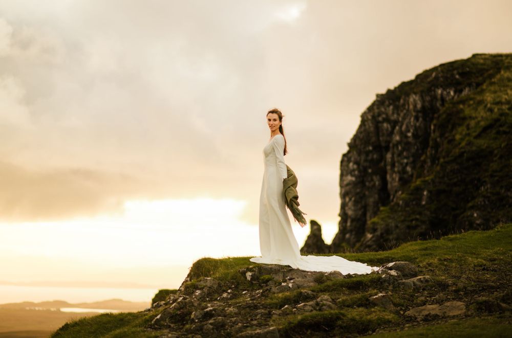 Bride on top of a cliff in Scottish Highlands' elopement at sunrise.
